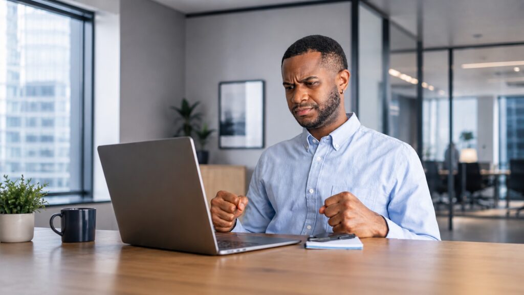 A professional looks at their laptop, frustrated.