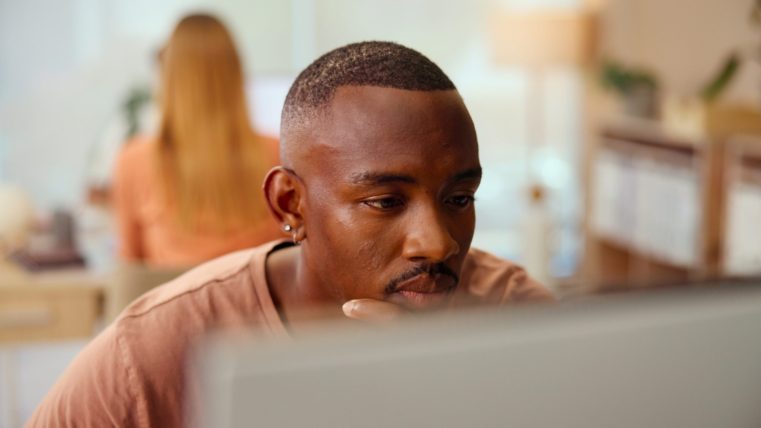 A bid professional looking at a computer screen, contemplating how to make benefits clearer to the buyer